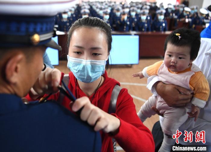 新消防員楊振的妻子彭莉與女兒現(xiàn)場見證丈夫加入“火焰藍”的神圣時刻?！⒅铱?攝