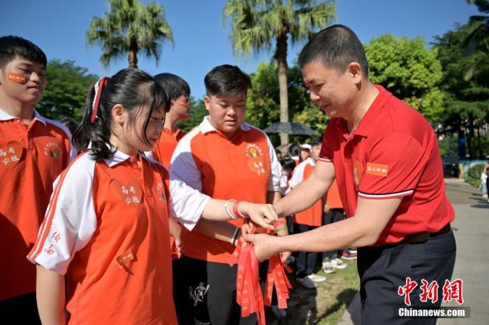 資料圖：廣西華僑實驗高中的教師為高三學(xué)子系上紅絲帶，盼望學(xué)子高考必勝。 俞靖 攝